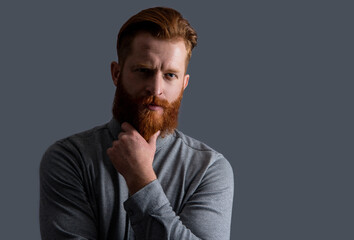 Portrait of serious man stroking beard. Bearded man with unshaven face. Irish man studio