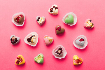 chocolate sweets in the form of a heart with fruits and nuts on a colored background. top view with space for text, holiday concept