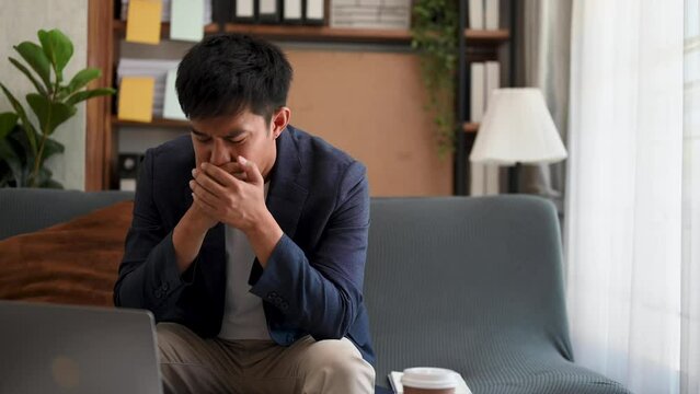 Frustrated young businessman working on a laptop computer sitting at his working place in home office