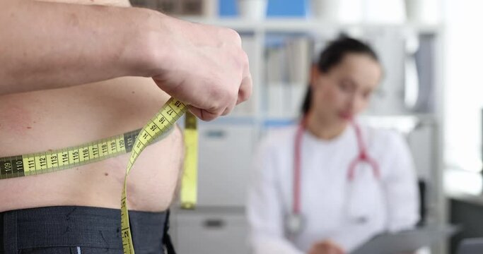 Man measuring his waist with tape at doctor appointment 4k movie. Treatment of abdominal obesity in men concept
