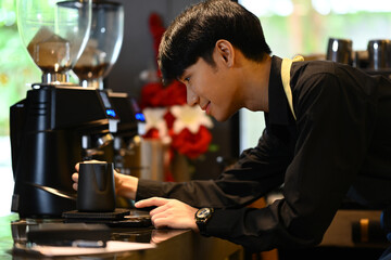 Concentrated male barista weighing raw materials on electronic scales, working in coffee shop