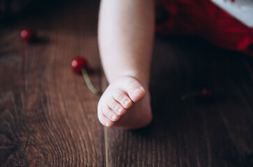 Child's foot on a brown background. Wooden background. Cherries Summer