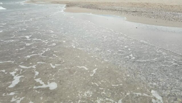 Slow motion of beach with clam shells on waves hitting the sand