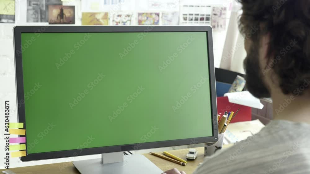 Poster Green screen computer display placed on wooden table in working room. Adult caucasian male working in front of monitor. Typing on the keyboard while writing code, text, copywriting, chatting.