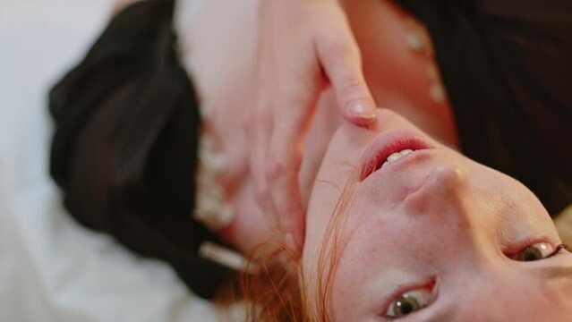 Seductive ginger girl touching her face and body while laying in bed wearing lingerie