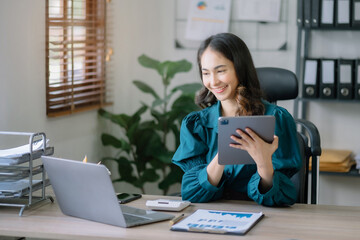 Businesswomen using tablet with laptop and document on desk in modern office.