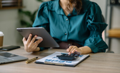 Businesswoman working with tablet and using a calculator to calculate the numbers of static in...