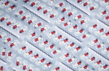 Full frame of white-red capsule pill in aluminum foil blister pack. Prescription drug....