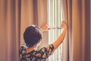 Woman open curtain in a bedroom.