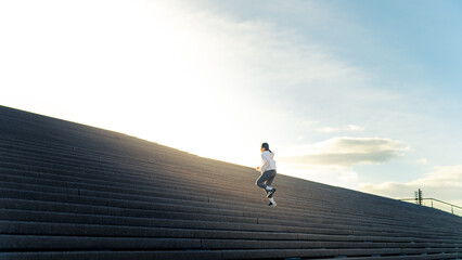 Attractive Asian woman in sportswear workout exercise jogging up on staircase at city street in the morning. Healthy girl enjoy outdoor active lifestyle do sport training fitness running in the city.