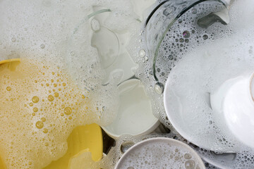 Dishes and bowls in water and bubbles of dishwashing liquid. Kitchen work