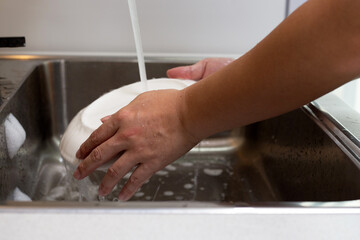 Man washing dish on sink in kitchen room