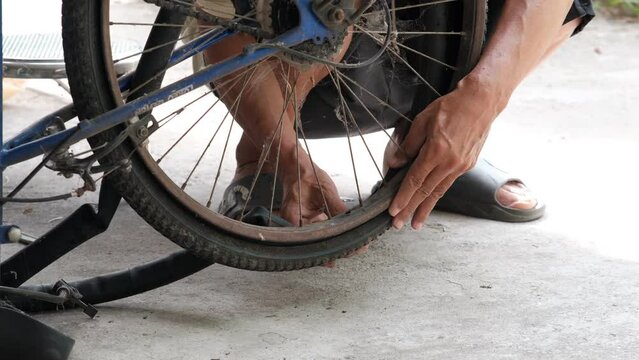 Old man mechanic repairs bicycle in workshop garage, Closed up old man worker Asian fixing old bicycle puncture 
