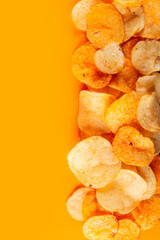 Border of potato chips isolated on orange colored background. Mouthwatering chip that is coated in...