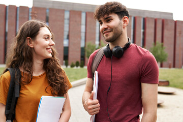 Two caucasian university students standing outside the university campus and talking