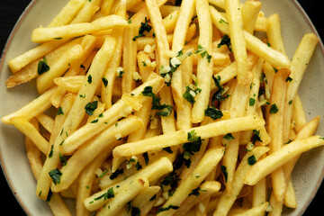 Garlic French Fries with Parsley on a Plate on a black background, top view. Overhead, from above, flat lay.
