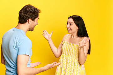 Big surprise and happiness. Young woman emotionally talking to her husband, expressing joy against yellow studio background. Concept of friendship, relationship, communication, emotions, lifestyle, ad