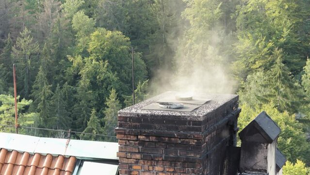 A chimney of a house emits rising smoke - closeup