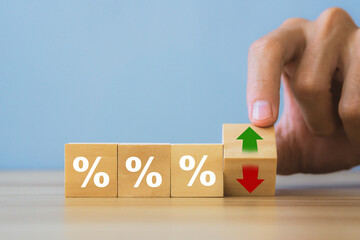 Interest rate,Financial and dividend concept.Hand holding wooden block with up-down arrow and percentage symbol.Inflation and tax concept.