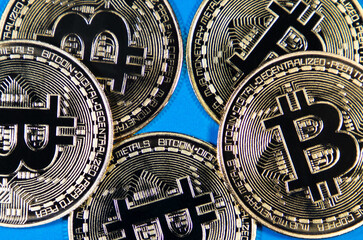 A closeup of some golden coins with bitcoin symbol on blue background. Cryptocurrency bit coin the future virtual currency