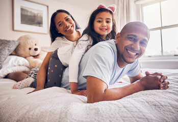 Family portrait, morning and relax on a bed at home while happy and playing for quality time. Man,...