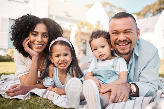 Portrait, blended family and parents on the lawn with their kids in the garden of their home together. Mother, father and children lying on the grass in the yard of their house for love or bonding