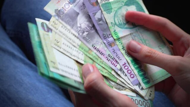 Woman took out Armenian dram banknotes and holds them in her hands, close-up. Cash Exchange Rates and Concept of Monetary Inflation. counts Armenian money close-up, Armenian dram and banknotes