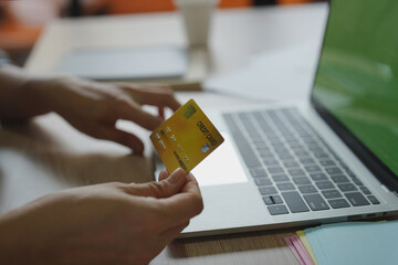 Side View using credit card to purchase shopping online from laptop.