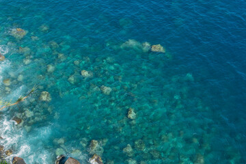 Fototapeta na wymiar Drone view of rocks and blue pristine sea with clear transparent water. Ocean background with copy space