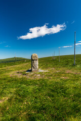 Old border stone on Vysoka hole hill with Praded hill on the background in Jeseniky mountains in Czech republic