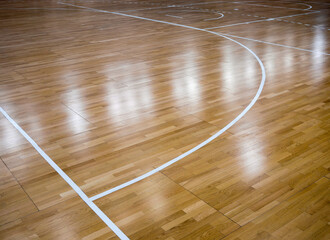 Parquet playing court for basketball with reflections of lanterns