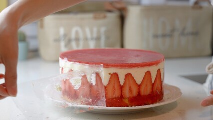 Close up view of female hands take the cake mold off the strawberry cake