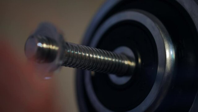 Close-up male hand adding weights on barbell in gym indoors. Closeup unrecognizable Caucasian young sportsman preparing equipment for training working out indoors