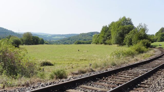 A train track curves through a countryside on a sunny day