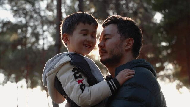 A loving father holding his son and and kissing him tenderly in nature 