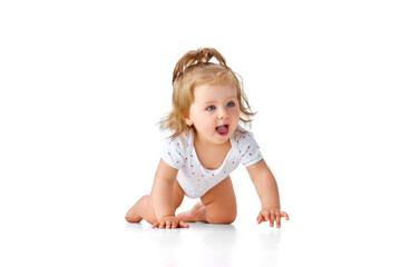 Beautiful, little, baby girl in diaper crawling on floor, playing against white studio background. Happy, smiling toddler
