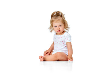 Questioning funny face. Cute, beautiful little girl, toddler sitting on floor with grimacing face against white studio background