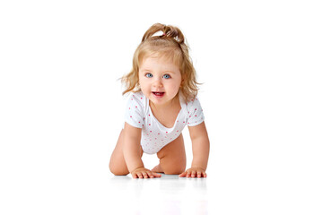 Happy, smiling, little, baby girl in diaper crawling on floor, playing against white studio background. Teeth