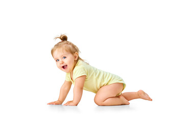 Cheerful, joyful, happy little baby, girl, toddler crawling and laughing against white studio background. Curious child