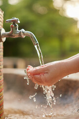 庭の水道水の蛇口で手洗いしている女性の両手の様子