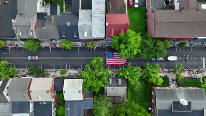 An American Independence Day parade marching through main street of town. Aerial top down view.