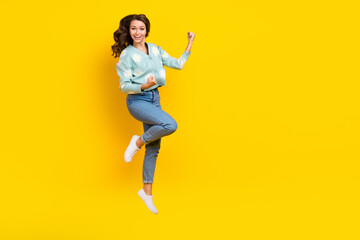 Fototapeta na wymiar Full length portrait of delighted pretty person jumping raise fists achieve isolated on yellow color background