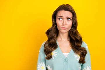 Photo of unsure pretty lady dressed teal cardigan looking emtpy space isolated yellow color...