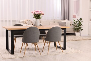 Table, chairs and vase with peonies in stylish dining room