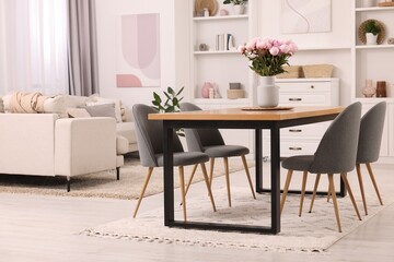 Fototapeta na wymiar Stylish dining room with cosy furniture and flowers