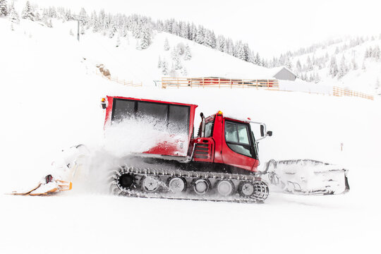 Red snowcat vehicle preparing ski slopes.