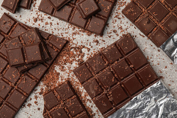 Pieces and shavings of tasty chocolate bars on light grey table, flat lay