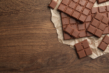 Pieces and crumbs of tasty chocolate bars on wooden table, top view. Space for text