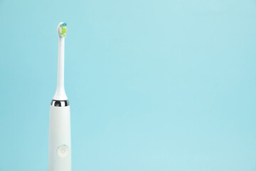Electric toothbrush on light blue background, space for text
