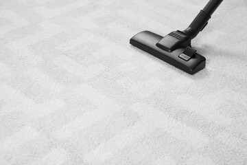 Hoovering white carpet with modern vacuum cleaner. Space for text